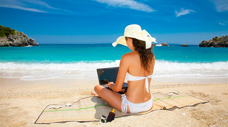 Beautiful woman with laptop computer on beach.