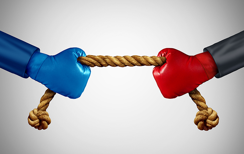 Tug of war as two opposing businessmen rivals pulling rope as a battle to win over an opponent and a test of business strength as a competition metaphor for financial strategy power between adversaries.